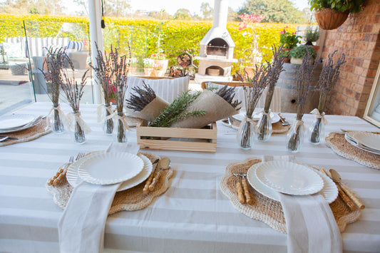 Outdoor table setting with white tablecloth, plates, and decorative elements.