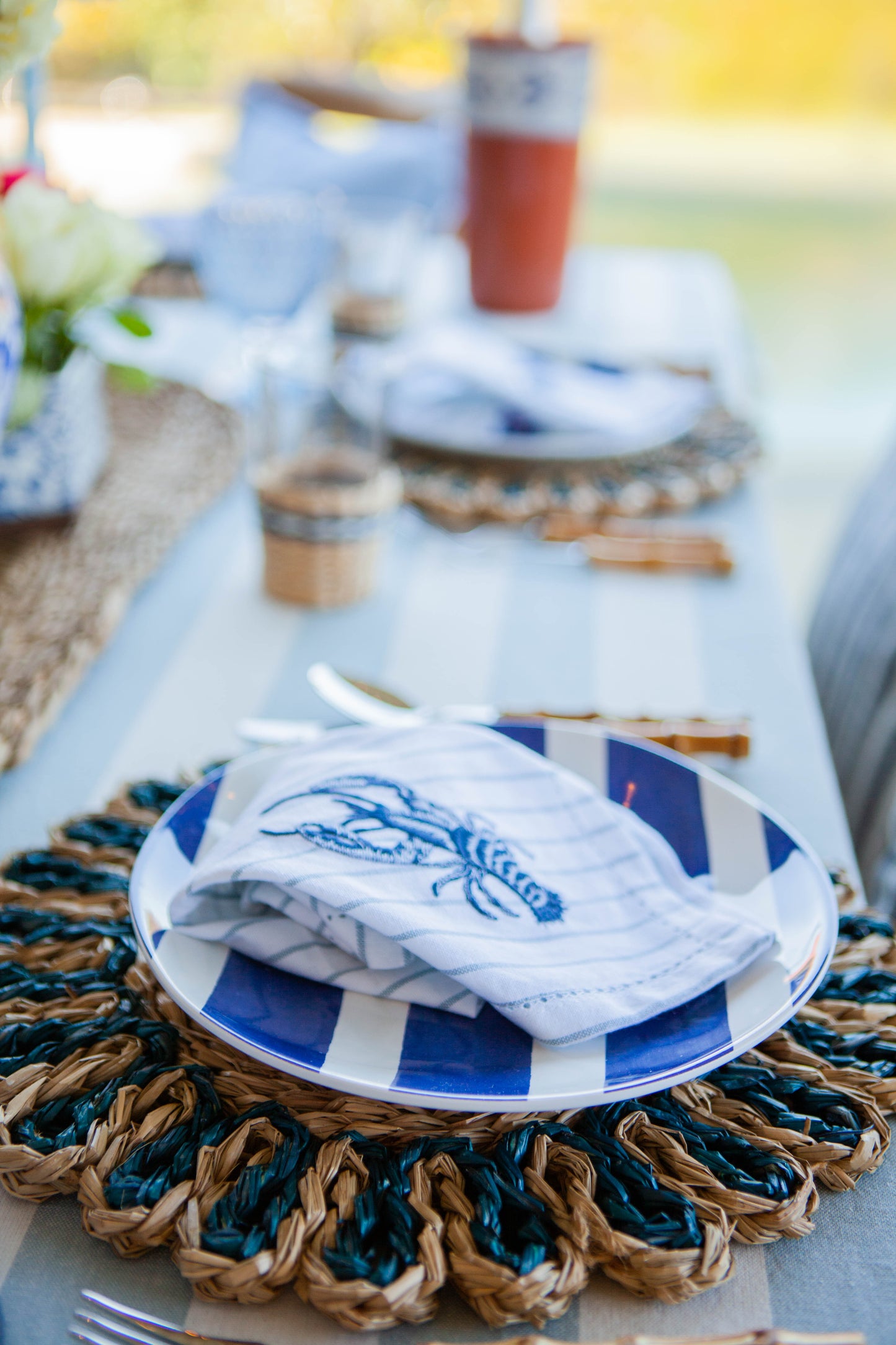 Table setting with blue and white plates, napkins, and a woven placemat.