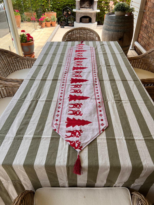 Table with olive green and white striped tablecloth and reindeer runner